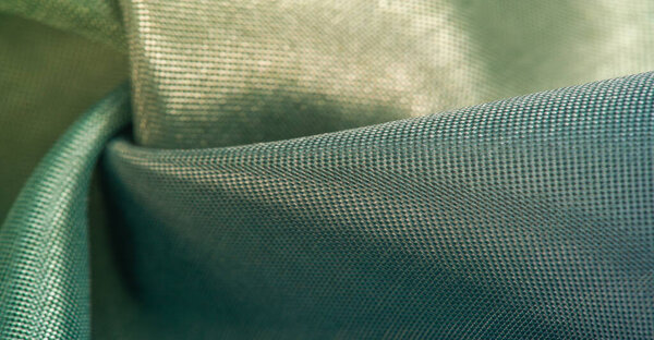 Фон текстуры, шелковая ткань, блестящий зеленый свет зеленого цвета, с небольшой абстрактной печати наскальных рисунков.