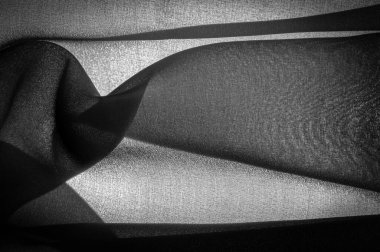 Arkaplan dokusu koyu siyah şifon ipeği yumuşak şeffaf bir kumaştır ve pürüzlüdür (matte, creped) çünkü bükülmüş iplik kullanımı.