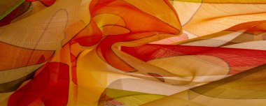 Arka plan dokusu bir organza deseni. İnce, şeffaf kumaştan bir kumaş. İnce, yapışkan ipekten bir peçe gibi. yeşil kırmızı kırmızı geometrik renkler