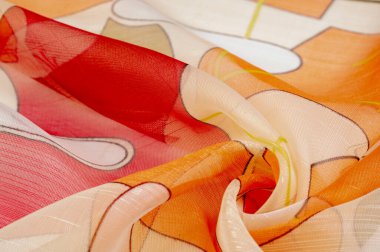Arka plan dokusu bir organza deseni. İnce, şeffaf kumaştan bir kumaş. İnce, yapışkan ipekten bir peçe gibi. yeşil kırmızı kırmızı geometrik renkler