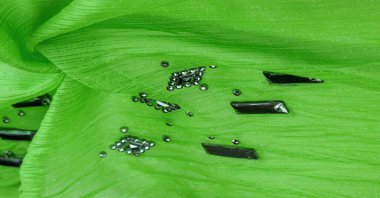 Arkaplan tasarımı dokusu, ipek desen, yeşil kumaş ve dekoratif işlemeli taşlar.