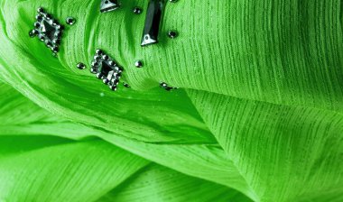 Arkaplan tasarımı dokusu, ipek desen, yeşil kumaş ve dekoratif işlemeli taşlar.