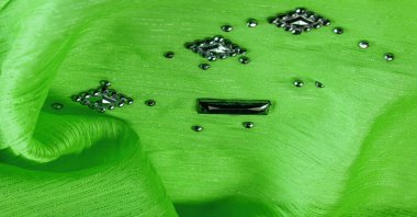 Arkaplan tasarımı dokusu, ipek desen, yeşil kumaş ve dekoratif işlemeli taşlar.