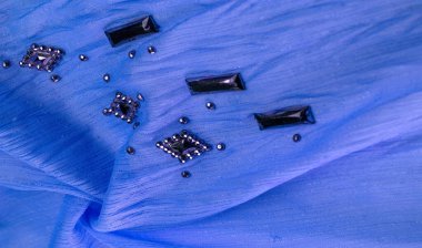 Arkaplan tasarımı dokusu, ipek desen, mavi kumaş ve dekoratif işlemeli taşlar.