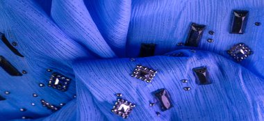 Arkaplan tasarımı dokusu, ipek desen, mavi kumaş ve dekoratif işlemeli taşlar.