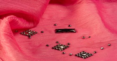 Arkaplan tasarımı dokusu, ipek desen, pembe kumaş ve dekoratif işlemeli taşlar.