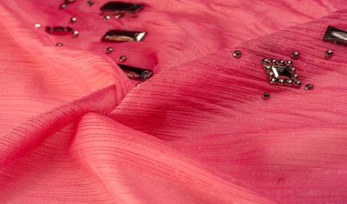 Arkaplan tasarımı dokusu, ipek desen, pembe kumaş ve dekoratif işlemeli taşlar.