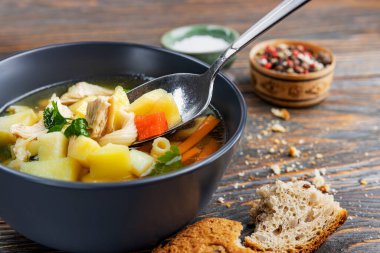 Tavuklu şehriye çorbası ve tahta tabakta otlar, sığ alan derinliği, seçici odaklanma. Sağlıklı ev beslenmesi kavramı.