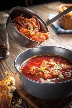 Sebzeli ve etli domates çorbası kepçe, lezzetli, iştah açıcı geleneksel Ukrayna borsch 'undan, yakın plan, sığ alan derinliği, seçici bir odak noktasından bir kaseye dökülür. Sağlıklı Ev Yapımı Organik