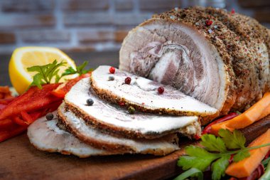 Geleneksel dilimlenmiş domuz eti otlar, limon havuçları ve baharatlarla süslenmiş, festival masasında servis için hazırlanmış, yakın plan, sığ alan derinliği, seçici odaklanma. Lezzetli kavramı