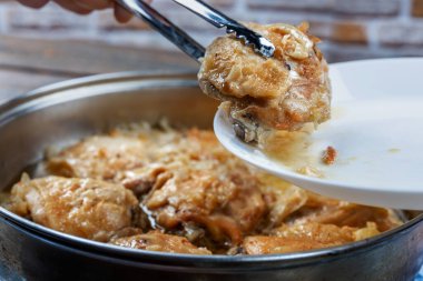 Tavuk butları tavada kızartılır ve tabakta tükürük ile servis edilir, yakın plan, yüzeysel alan derinliği, seçici odaklanma. Ev yapımı gıda konsepti.