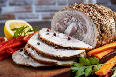 Geleneksel dilimlenmiş domuz eti otlar, limon havuçları ve baharatlarla süslenmiş, festival masasında servis için hazırlanmış, yakın plan, sığ alan derinliği, seçici odaklanma. Lezzetli kavramı