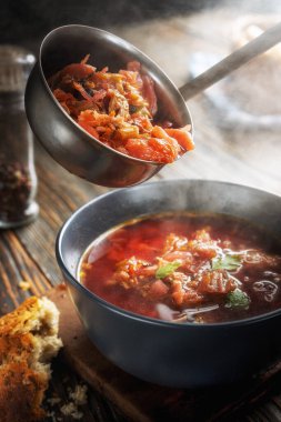 Sebzeli ve etli domates çorbası, buharın geldiği yerden bir kaseye dökülüyor, lezzetli, iştah açıcı geleneksel Ukrayna borsch 'u, yakın plan, sığ alan derinliği, seçici odaklanma.