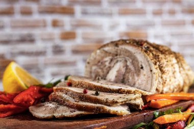 Geleneksel dilimlenmiş domuz eti otlar, limon havuçları ve baharatlarla süslenmiş, festival masasında servis için hazırlanmış, yakın plan, sığ alan derinliği, seçici odaklanma. Lezzetli kavramı