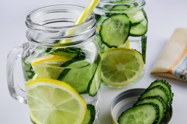 Soğuk içecek, beyaz arka planda salatalık ve limonlu iki retro cam bardak limonata, sığ alan derinliği, seçici odaklanma. Sağlık içeceği kavramı.