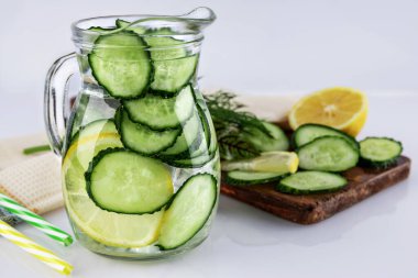 Salatalık ve limondan yapılan soğuk içecek, beyaz arka planda sürahide ev yapımı limonata, sığ alan derinliği, seçici odaklanma. Sağlıklı içki konsepti