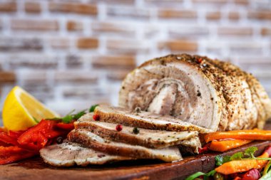 Geleneksel dilimlenmiş domuz eti otlar, limon havuçları ve baharatlarla süslenmiş, festival masasında servis için hazırlanmış, yakın plan, sığ alan derinliği, seçici odaklanma. Lezzetli kavramı