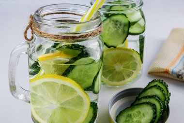 Soğuk içecek, beyaz arka planda salatalık ve limonlu iki retro cam bardak limonata, sığ alan derinliği, seçici odaklanma. Sağlık içeceği kavramı.