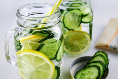 Soğuk içecek, beyaz arka planda salatalık ve limonlu iki retro cam bardak limonata, sığ alan derinliği, seçici odaklanma. Sağlık içeceği kavramı.