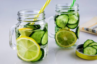 Soğuk içecek, beyaz arka planda salatalık ve limonlu iki retro cam bardak limonata, sığ alan derinliği, seçici odaklanma. Sağlık içeceği kavramı.