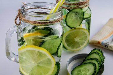 Soğuk içecek, beyaz arka planda salatalık ve limonlu iki retro cam bardak limonata, sığ alan derinliği, seçici odaklanma. Sağlık içeceği kavramı.