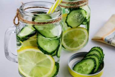 Soğuk içecek, beyaz arka planda salatalık ve limonlu iki retro cam bardak limonata, sığ alan derinliği, seçici odaklanma. Sağlık içeceği kavramı.