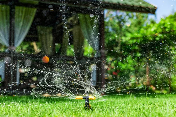 Sulama bahçesinin modern aygıtı. Sulama sistemi. Bahçede sulama tekniği. Çim püskürtücü yeşil çimlerin üzerine su püskürtüyor.. — Stok fotoğraf