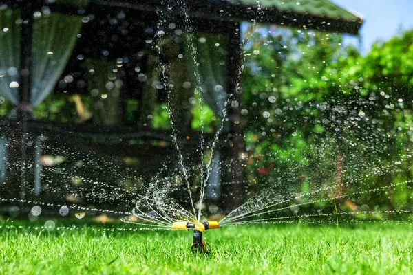 灌漑庭園の近代的な装置。灌漑システム-庭に水をやる技術。芝生のスプリンクラーは緑の草の上に水を噴霧. — ストック写真