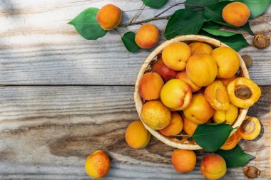 Tahta tahtalarda sepetin içinde kayısılar, yukarıdan aşağıya doğru. Taze meyve kavramı