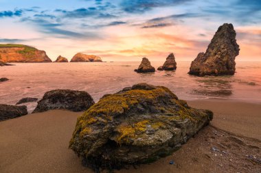 Scenic sunset view at Rodeo Beach in Marin Headlands, California. Dramatic sea stacks and ocean waves glowing in warm evening light, creating a peaceful coastal landscape along Highway 1