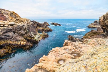 Rocky coastal inlet along Highway 1 in Big Sur, California. Rugged cliffs and dramatic rock formations frame turquoise Pacific waters, creating a wild and secluded passage on the scenic Pacific Coast Highway
