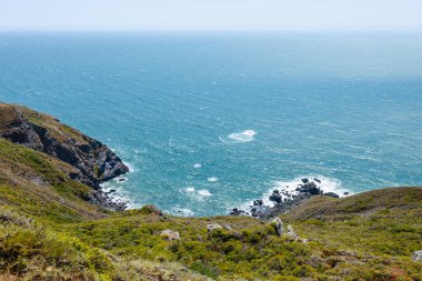 Scenic view from Tennessee Valley Trail in Marin Headlands, California. Rolling green and golden hills open toward the Pacific Ocean with distant views of San Francisco and the Bay Area skyline