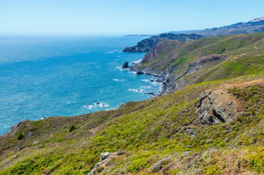 Scenic view from Tennessee Valley Trail in Marin Headlands, California. Rolling green and golden hills open toward the Pacific Ocean with distant views of San Francisco and the Bay Area skyline