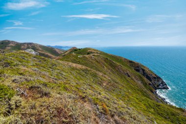 Scenic view from Tennessee Valley Trail in Marin Headlands, California. Rolling green and golden hills open toward the Pacific Ocean with distant views of San Francisco and the Bay Area skyline