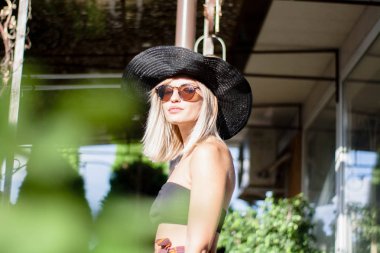 Elegance şık gülümseyen ve şapka ve güneş gözlüğü yürüyüş sokak ve kamera, duygular poz gülen genç kadın moda portre