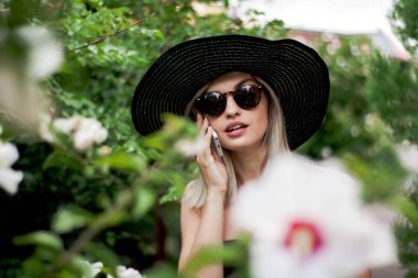 Şapka ve gözlük bir akıllı telefon kullanan genç şık güzel kadın selfie açık havada yapma