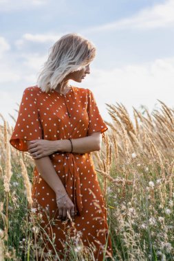 Eğleniyor ve sahada günbatımında poz neşeli güzel genç kadın