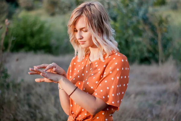 Młoda Blond Kobieta Patrząc Ręce Golden Błyszczy Polu Zachód Słońca — Zdjęcie stockowe