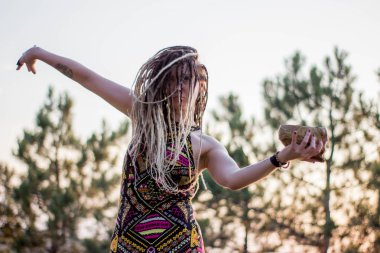 Genç güzel hippi kadın insan kafatası ile vahşi dans alanında günbatımında dans dreadlocks ile