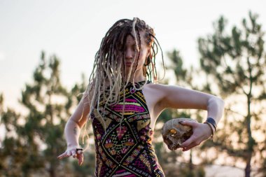 Genç güzel hippi kadın vahşi dans alanında günbatımında dreadlocks ile