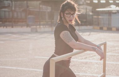 gözlük ve denim ceket şık bir güzel genç kadın portresi. Gülümseyen ve gün batımında poz. Kentsel