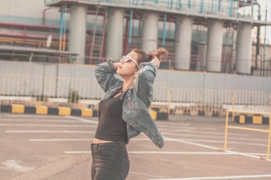 gözlük ve denim ceket şık bir güzel genç kadın portresi. Gülümseyen ve gün batımında poz. Kentsel