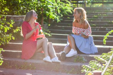 İki çekici güzel genç sarışın kadın parkta darbe bubbles ve sunset Bulvarında mutluyuz. Kız adımları Park'ta