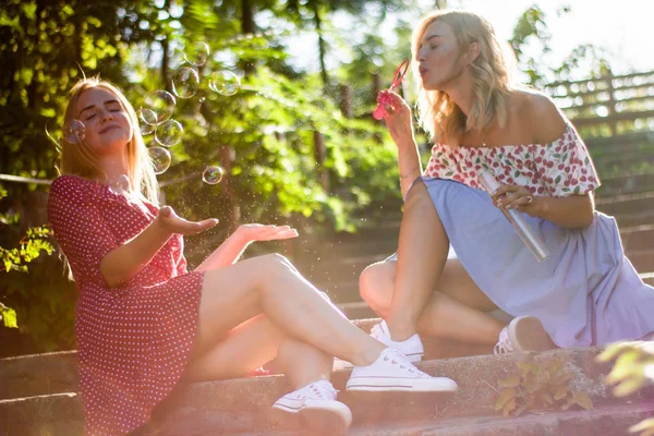 魅力的な美しい若い金髪女性は公園でシャボン玉を吹くし 夕日に満足しています 手順上の公園のガール フレンド — ストック写真