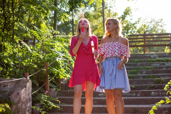 Две Привлекательные Красивые Молодые Блондинки Дуют Пузыри Парке Счастливы Закате — стоковое фото