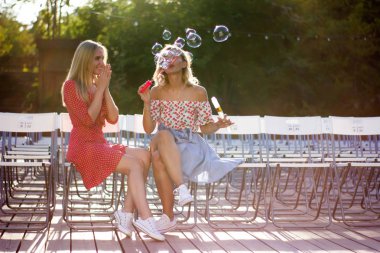 İki çekici güzel genç sarışın kadın parkta darbe bubbles ve sunset Bulvarında mutluyuz. Park kız.