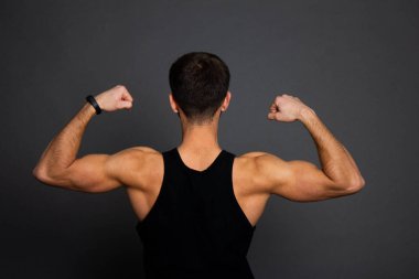 Yakışıklı genç adam ayakta güçlü siyah arka planda esneme kasları - ve kaslı atletik vücut geliştirmeci Fitness Model poz sonra egzersizleri. vücut geliştirme