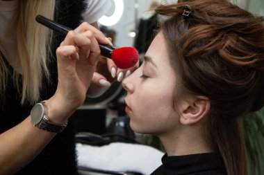 Genç kadın profesyonel makyaj yapıyor sanatçı makyaj, yakın çekim. Güzellik Salonu iç genç kadın portresi. Güzellik moda modeli.