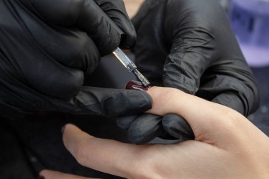 İşlem manikür. Bir kadın elleri ve çivi bir kadının üzerinde çalışıyor. Yakın çekim