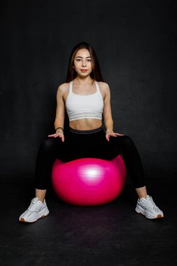 Atletik ve güçlü genç kadın bazı egzersiz fitness Ball siyah bir arka plan yapmak